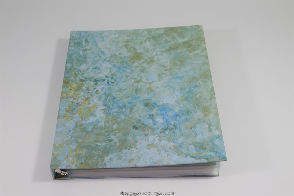 baby book - a three-ring binder with a marbled green and blue cover filled with laminated baby book pages