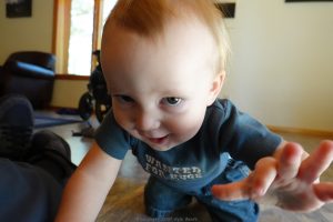 A happy baby crawling who has almost reached the camera lens